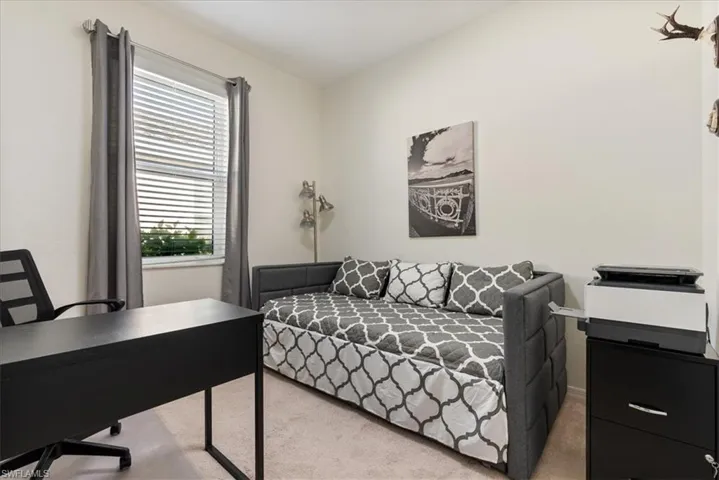 Carpeted bedroom featuring an office area