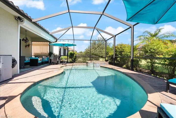 View of pool with a patio, a pool with connected hot tub, and glass enclosure