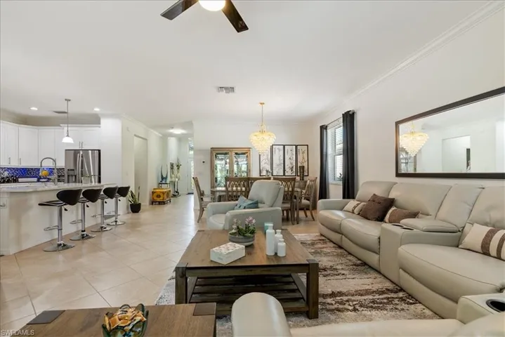 Living room featuring light tile patterned floors, crown molding, ceiling fan, a chandelier, and recessed lighting