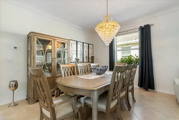 Dining room with ornamental molding, a chandelier, and light tile patterned floors