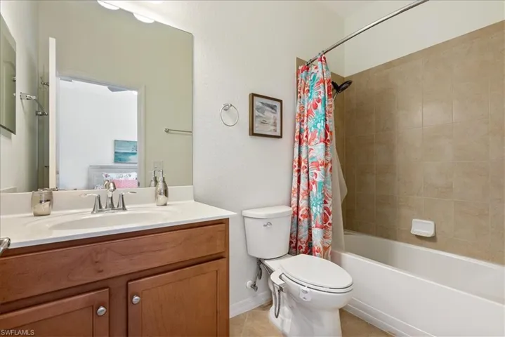 Full bath featuring vanity, shower / tub combo with curtain, and tile patterned floors