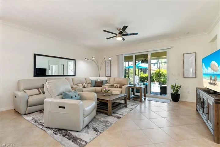 Living room featuring a ceiling fan, ornamental molding, and light tile patterned flooring