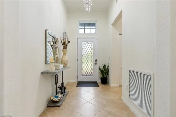 Entryway with ornamental molding, light tile patterned floors, and a high ceiling