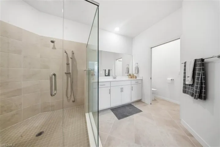 Full bathroom with vanity, a stall shower, and light tile patterned floors