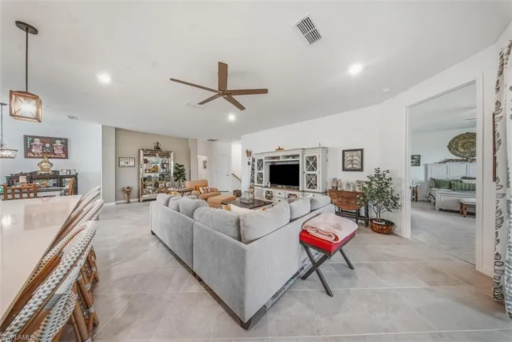 Living room with ceiling fan, light tile patterned flooring, and recessed lighting