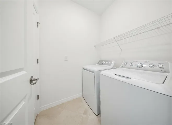 Laundry room with light tile patterned floors and washing machine and clothes dryer