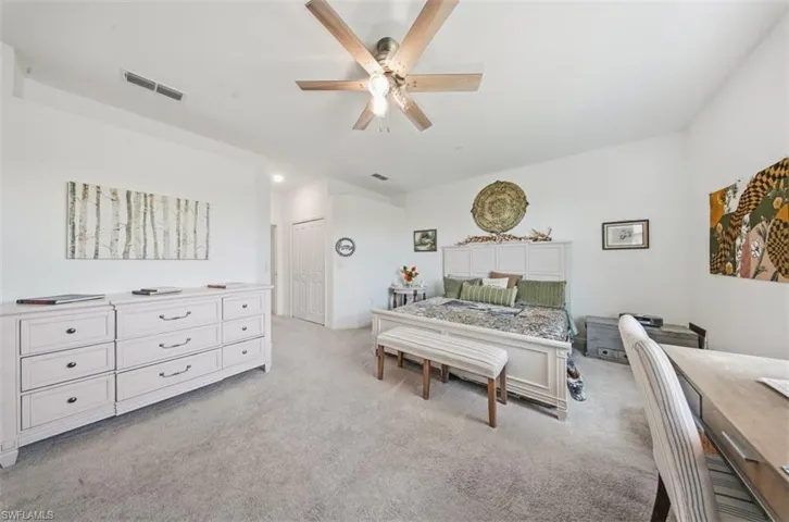 Bedroom featuring light colored carpet, a ceiling fan, and a closet