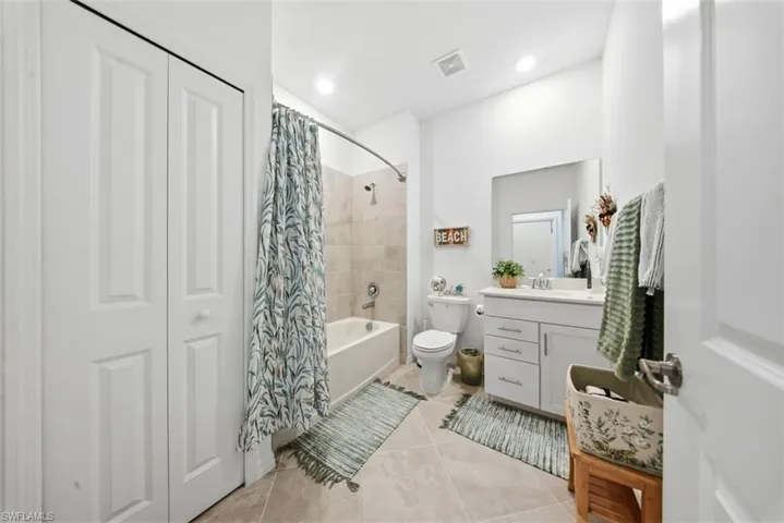 Full bath featuring vanity, shower / tub combo, light tile patterned flooring, and a closet