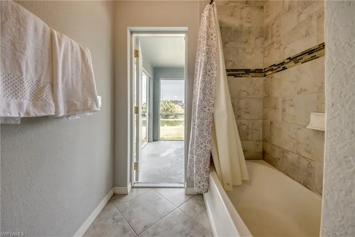 Bathroom featuring a tiled tub surround with an accent band, a white tub, and neutral wall paint