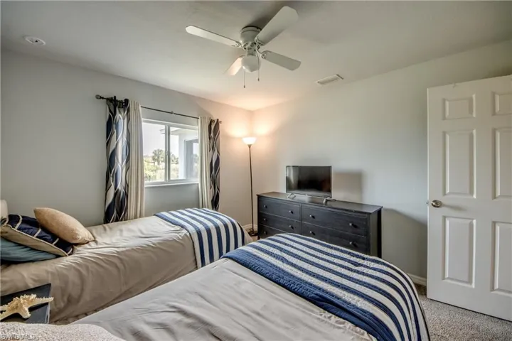 Carpeted room featuring a ceiling fan with integrated lighting, a window with a white frame, and a paneled white door