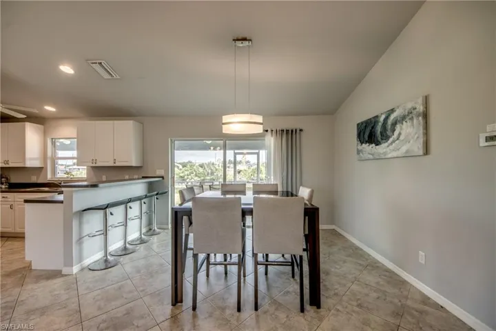 Open-concept dining area featuring tile flooring, a modern pendant light fixture, and sliding glass doors