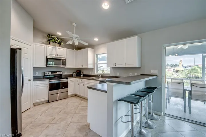 Modern kitchen featuring white cabinetry, stainless steel appliances, a breakfast bar, recessed lighting, and tile flooring
