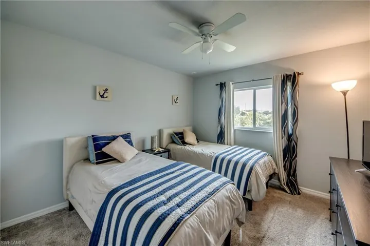 Carpeted room with a ceiling fan, a window with dark patterned drapes, and light gray walls