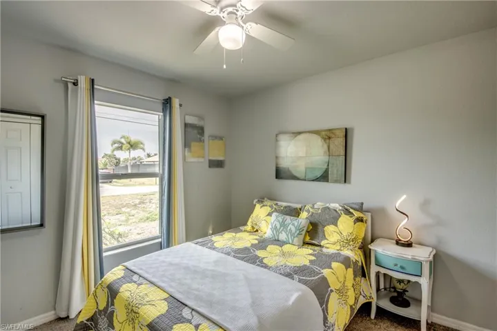 Bedroom featuring a window with natural light, textured walls, ceiling fan, and carpet flooring