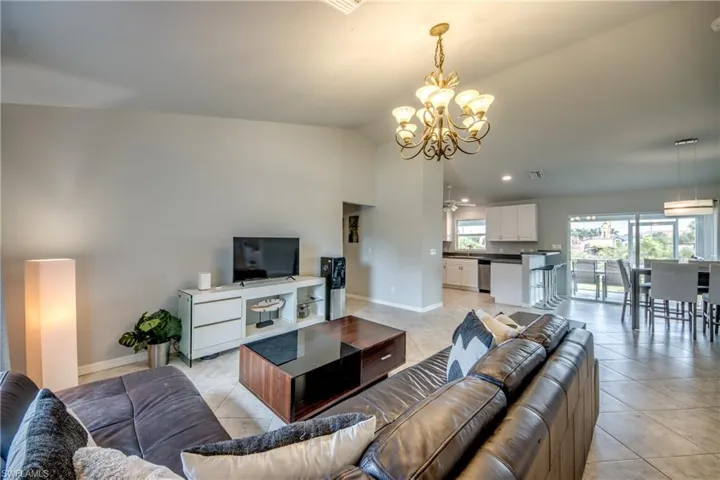 Spacious living area featuring neutral wall tones, tile flooring, a decorative chandelier, and recessed lighting