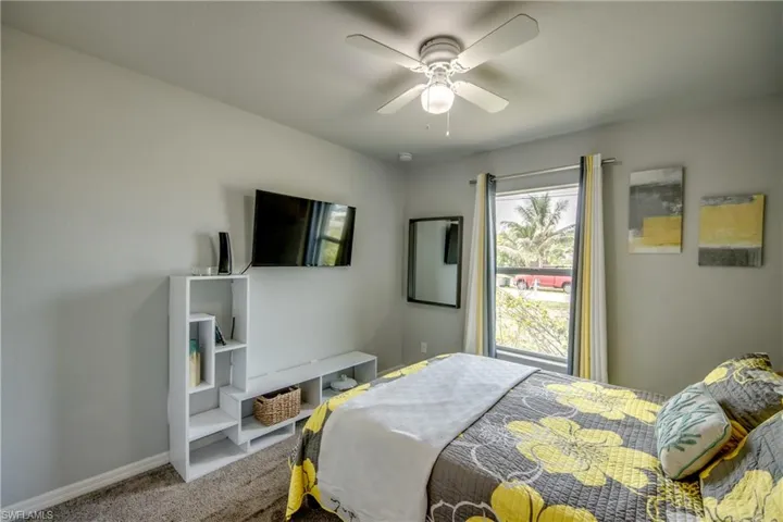 Bedroom featuring neutral wall tones, a ceiling fan with integrated lighting, and a window with vertical blinds