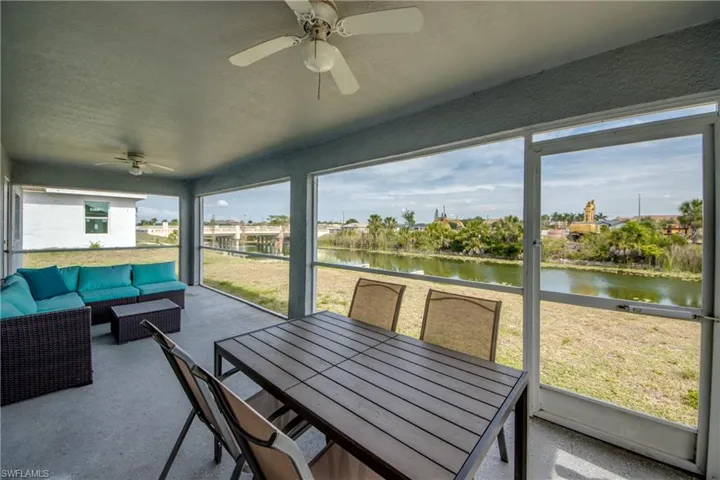 Screened outdoor living area with concrete flooring, multiple ceiling fans, and a water-facing orientation