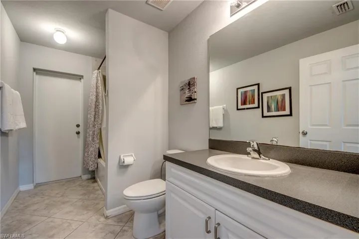 Bathroom featuring a vanity with an oval sink, dark countertop, and a large mirror