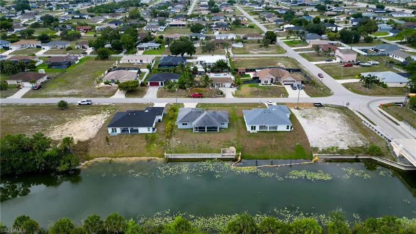 Canal-front property featuring a concrete seawall and adjacent bridge access