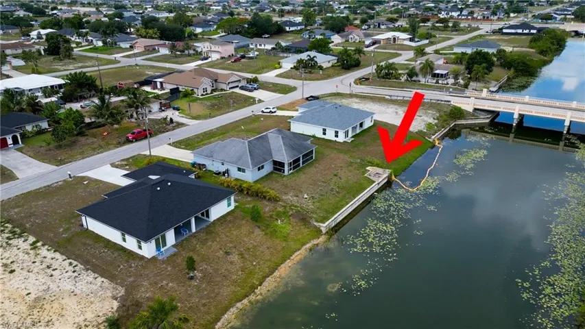 Waterfront property featuring a concrete seawall, direct canal access, and a concrete boat ramp