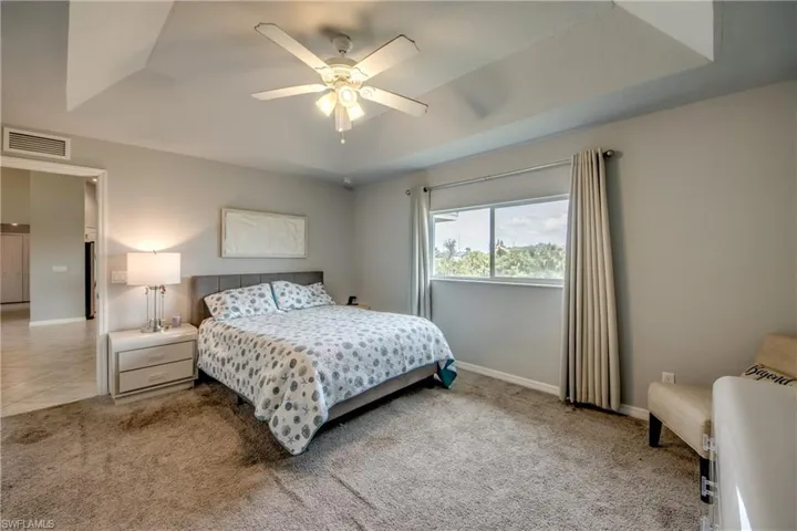 Room featuring a tray ceiling with a ceiling fan, recessed window, and wall-to-wall carpeting