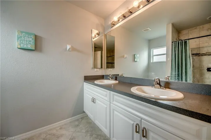 Bathroom featuring a dual vanity with white cabinetry, dark countertops, and integrated sinks