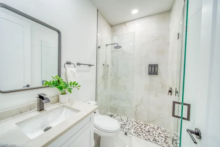 Bathroom featuring a marble finish shower, vanity, and recessed lighting