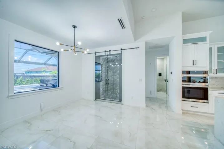Empty room featuring a chandelier and light marble finish floors