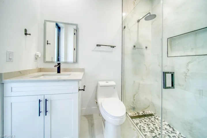 Bathroom with a marble finish shower, vanity, and light tile patterned floors