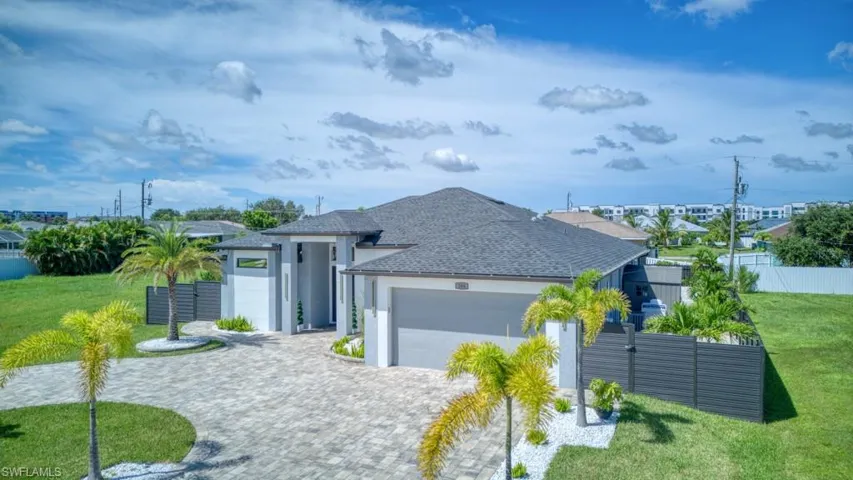 View of front of home featuring a shingled roof, stucco siding, decorative driveway, and an attached garage