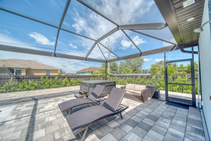 Fenced backyard with a lanai, a hot tub, a sunroom, and a patio area