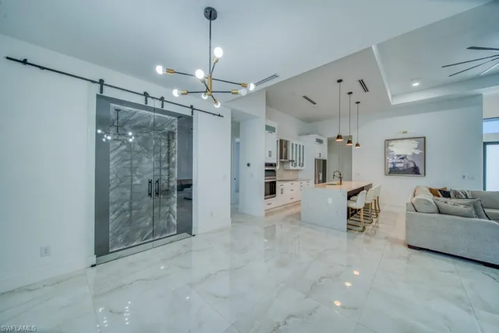Living area with a chandelier, light marble finish floors, and a barn door