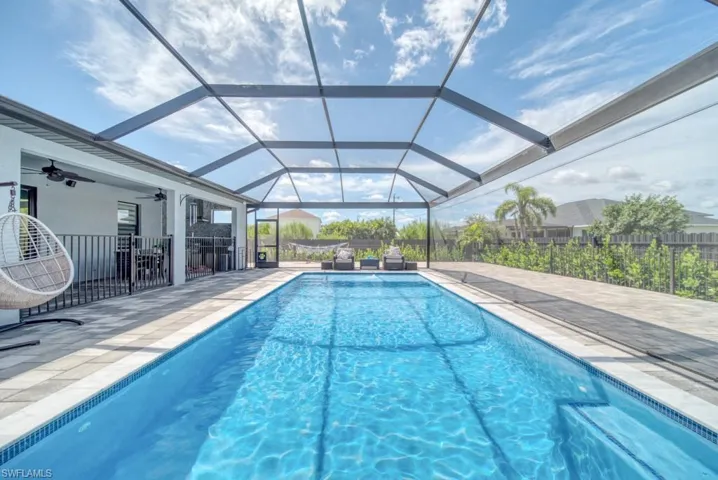 View of pool with a sunroom, a patio, ceiling fan, and glass enclosure