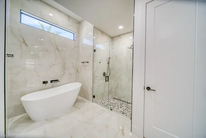 Bathroom featuring a marble finish shower, a freestanding bath, recessed lighting, marble tiled floors, and tile walls