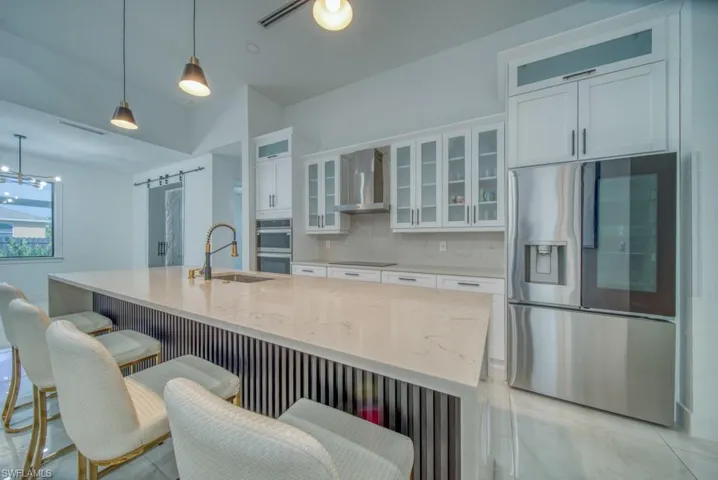 Kitchen with a barn door, light stone countertops, stainless steel appliances, and white cabinets