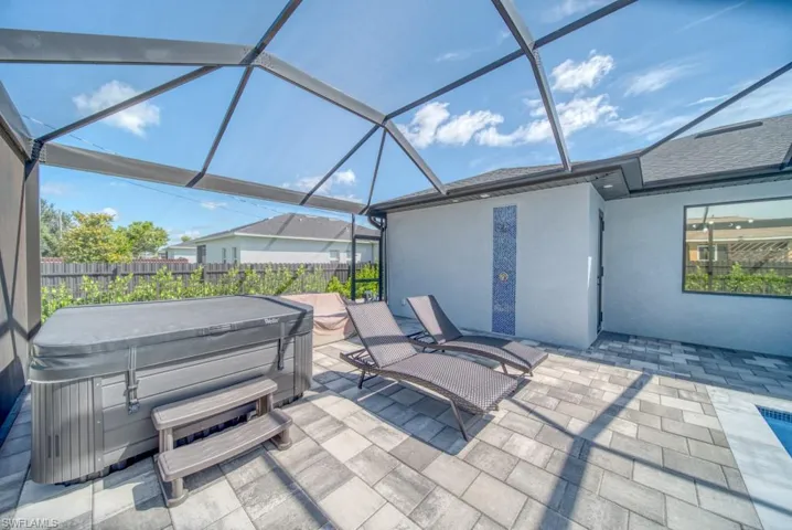 View of patio / terrace with a hot tub, a sunroom, and a lanai