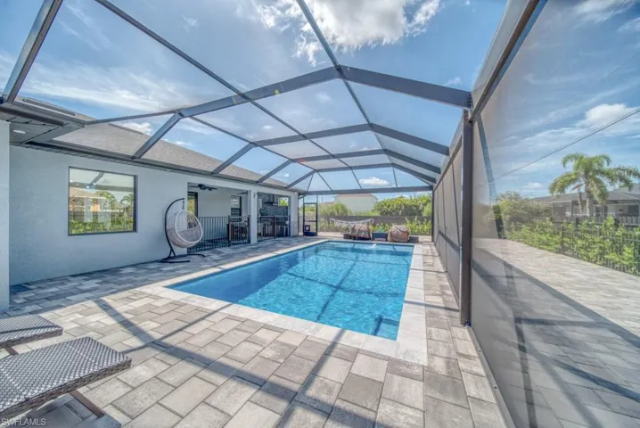 Swimming pool with a sunroom, a patio area, glass enclosure, and ceiling fan