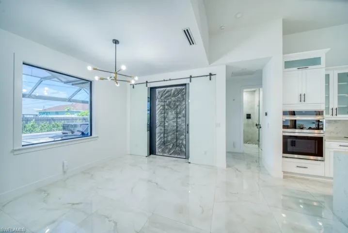Spare room with a chandelier and light marble finish floors