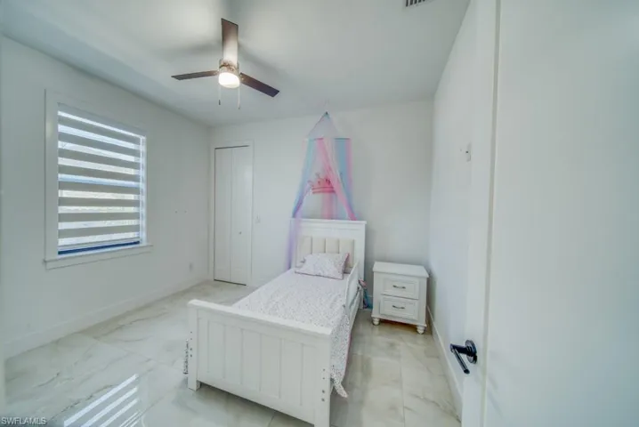 Bedroom with ceiling fan and light marble finish floors