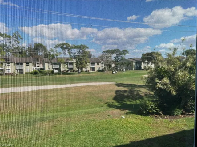 View of grassy yard featuring view of golf course and a residential view