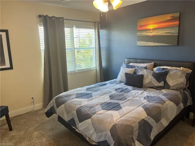 Carpeted bedroom with a ceiling fan and baseboards