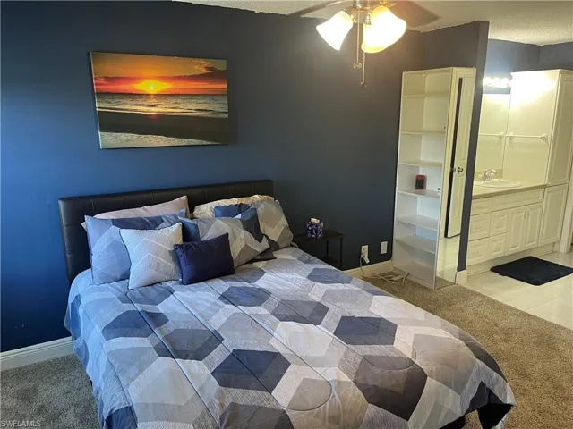 Bedroom featuring light carpet, connected bathroom, ceiling fan, and a textured ceiling