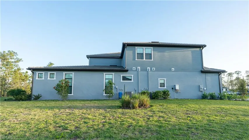 Back of house with a yard and stucco siding