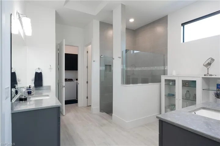 Full bathroom featuring recessed lighting, baseboards, walk in shower, vanity, and separate washer and dryer