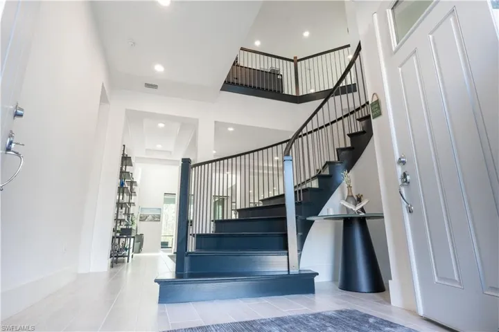 Stairway with recessed lighting, baseboards, visible vents, tile patterned flooring, and a high ceiling