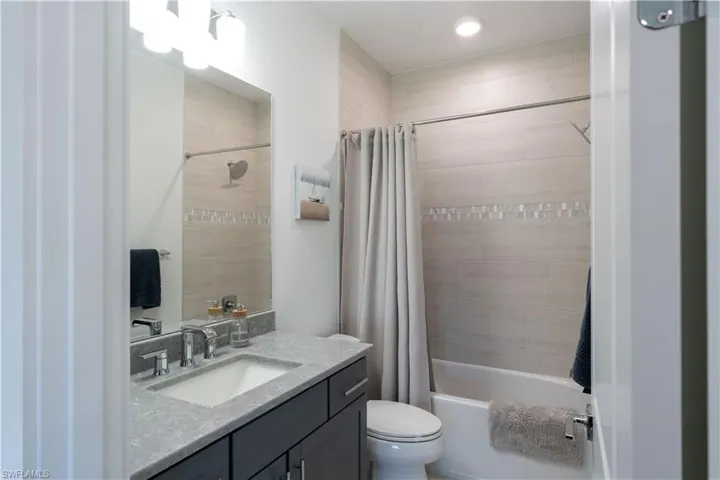Full bath with vanity, toilet, shower / bathtub combination with curtain, and recessed lighting
