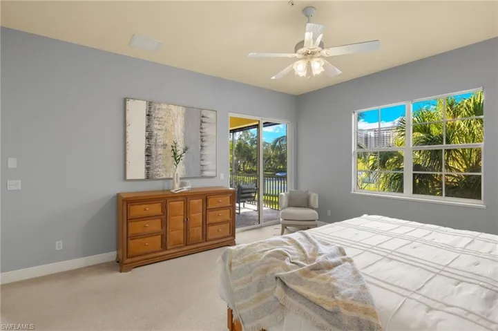 Bedroom with light colored carpet, multiple windows, baseboards, and access to exterior