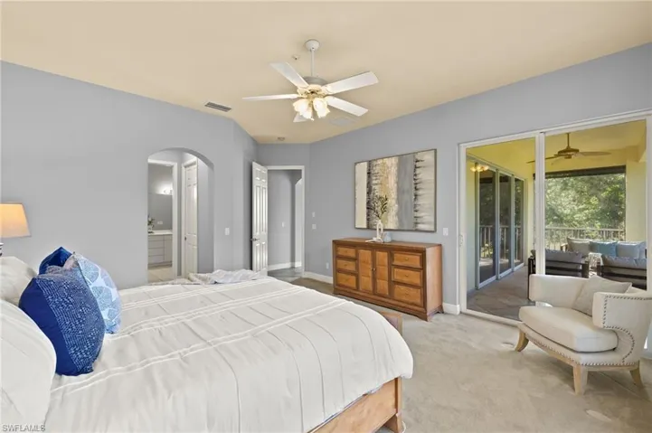 Bedroom with carpet floors, visible vents, baseboards, arched walkways, and access to outside