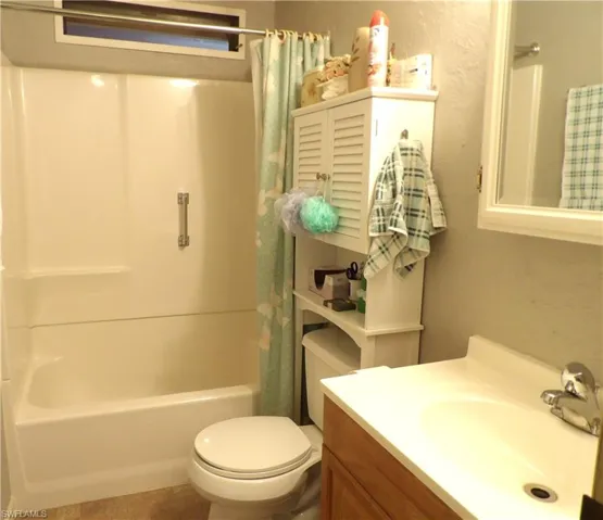 Full bathroom with vanity, shower / tub combo, tile patterned floors, and a textured wall