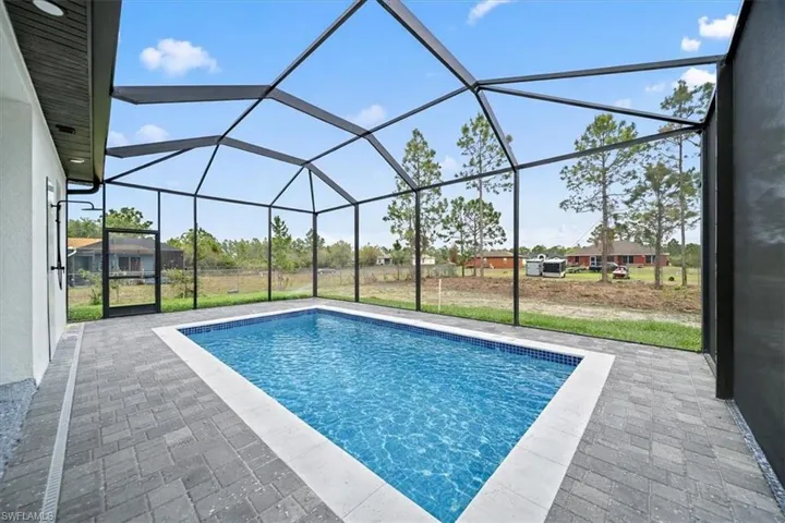 Swimming pool with a sunroom, a patio, a lanai, and a lawn